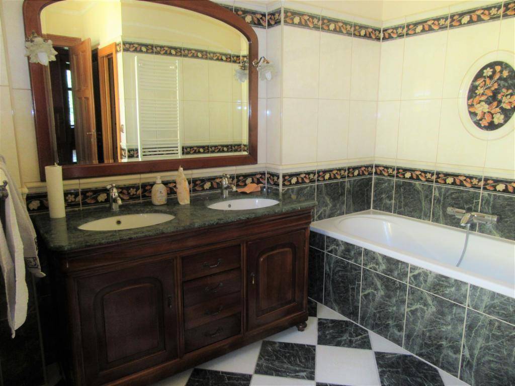 Badezimmer mit Doppelwaschbecken, Badewanne und dekorativen Fliesen, klassisches Design.