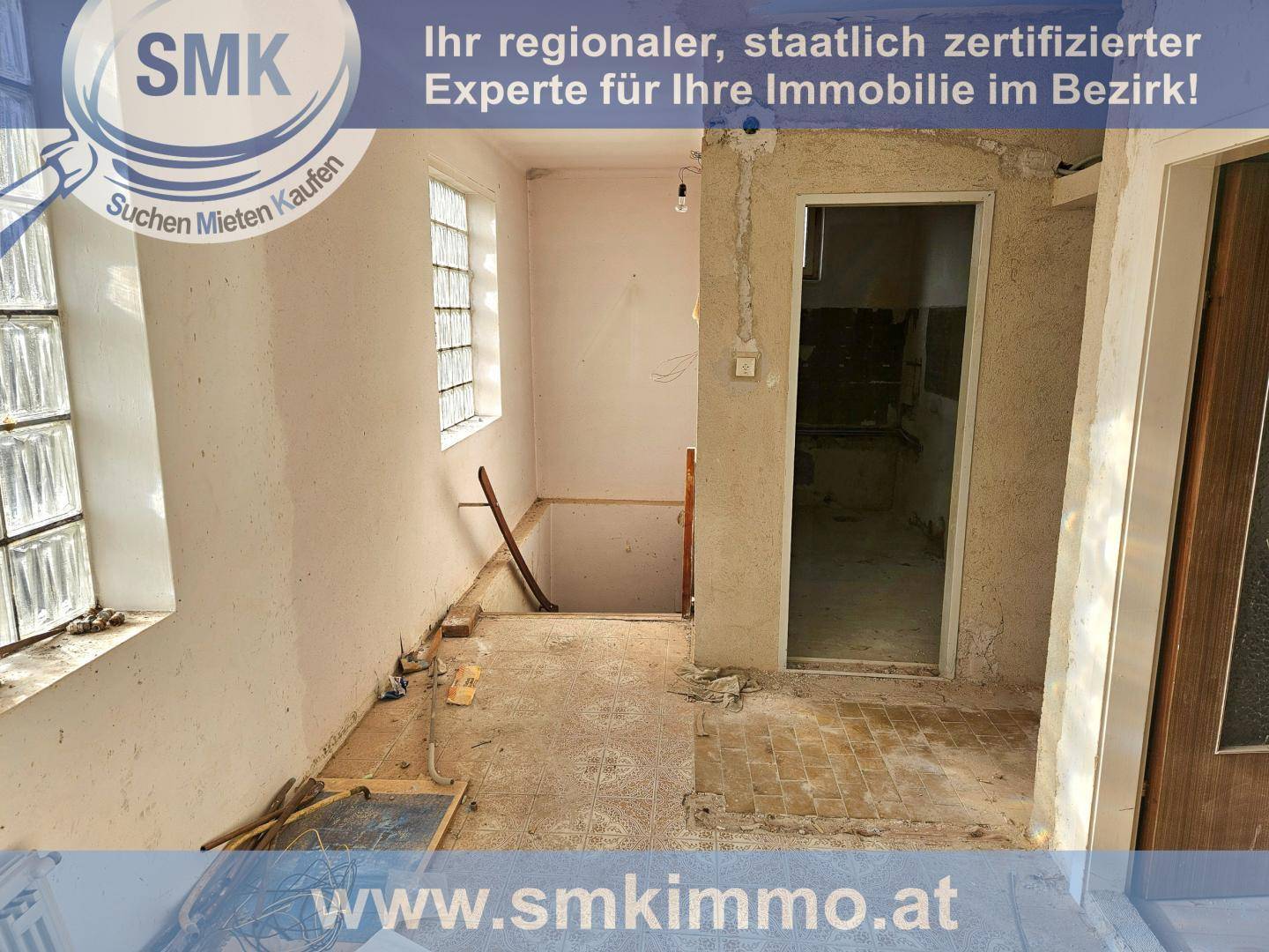 Flur im Rohbau mit Glasbausteinen und Treppenabgang, bereit für den weiteren Ausbau.