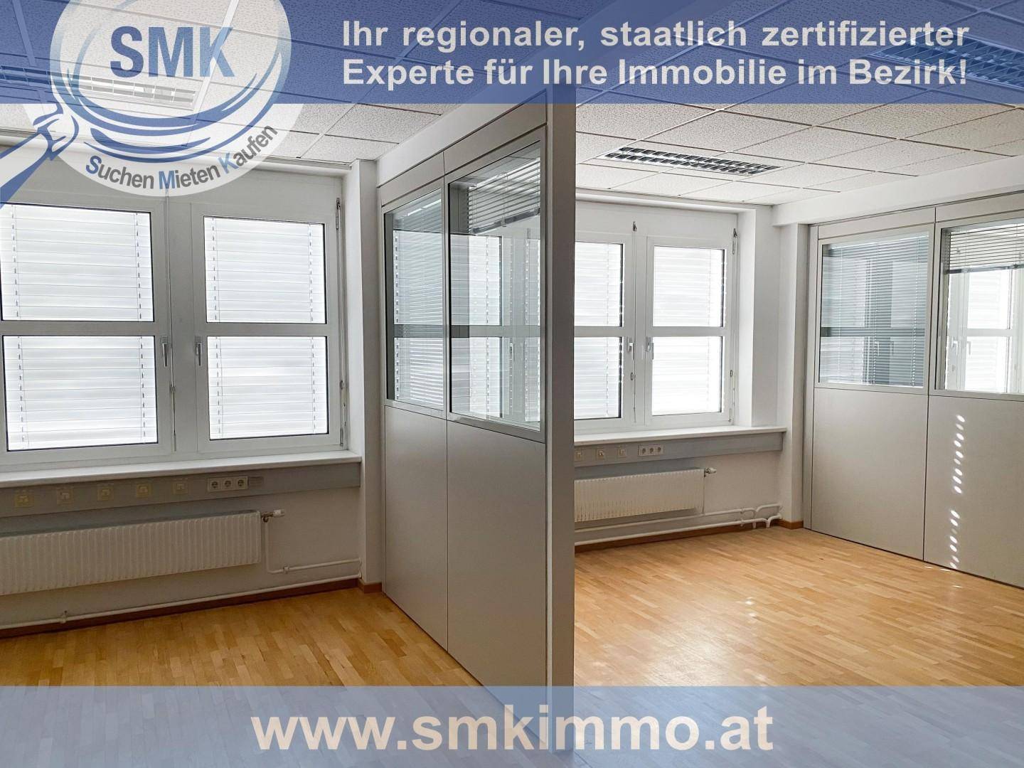 Offener Bürobereich mit flexiblen Trennwänden, großen Fenstern und Holzfußboden, der verschiedene Arbeitszonen schafft.