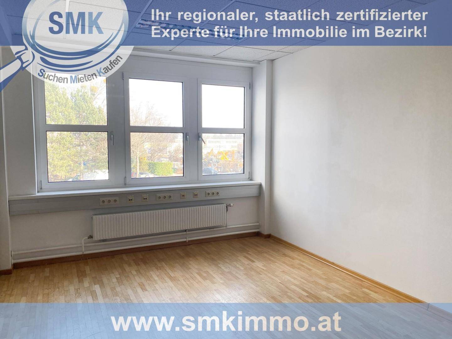 Helles, leeres Büro mit großen Fenstern, die viel Tageslicht hereinlassen, und einem gepflegten Holzfußboden.