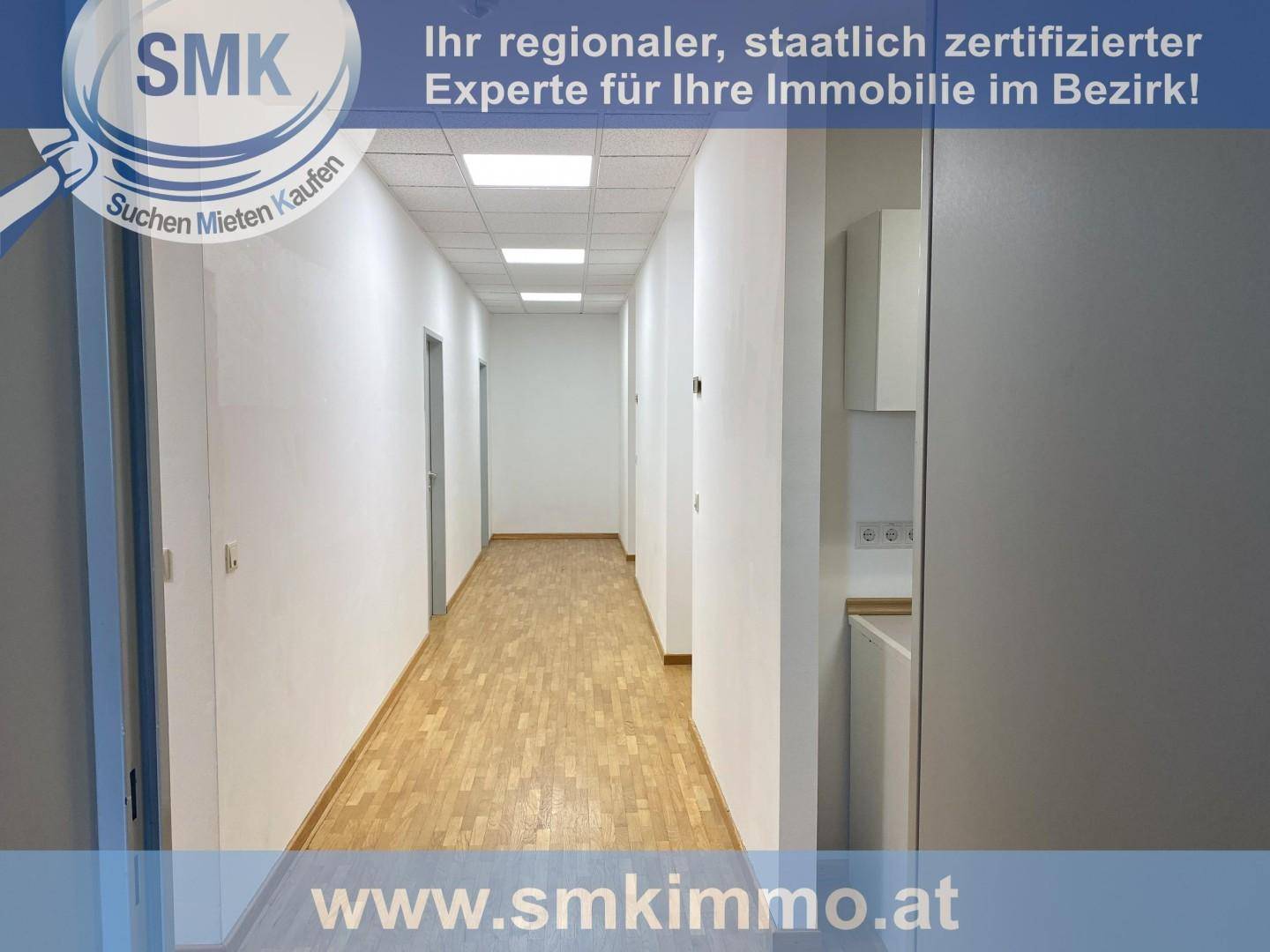 Langer, heller Flur mit Türen zu verschiedenen Räumen, Holzfußboden und integrierter kleiner Küchenzeile.