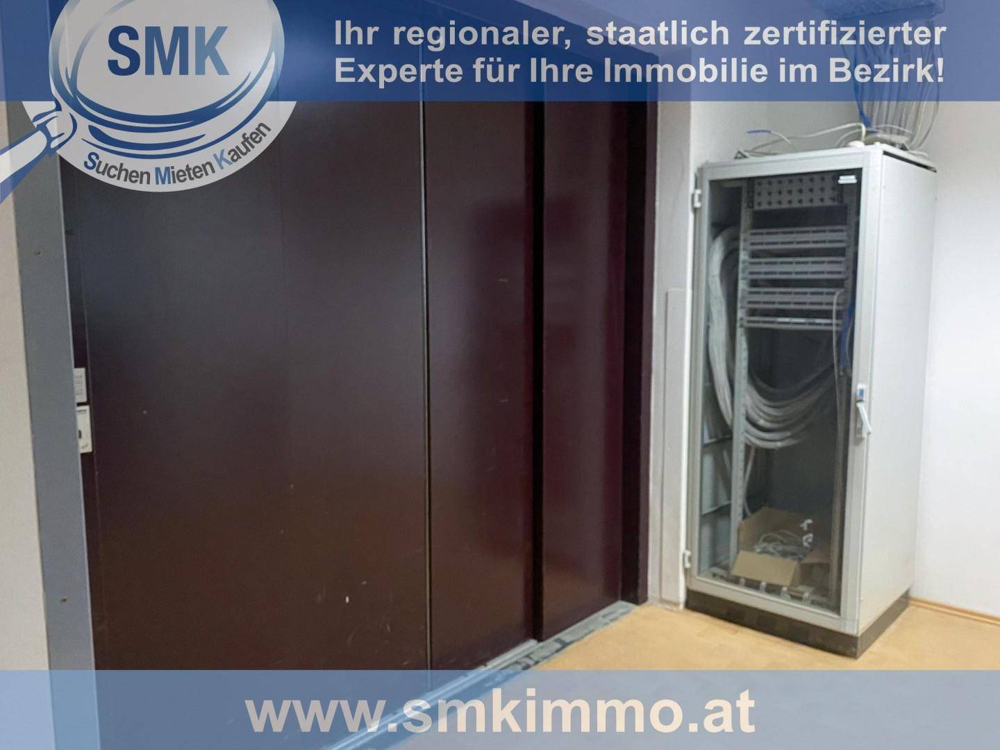 Aufzugstür neben einem offenen Serverschrank mit Verkabelung in einem Servicebereich des Gebäudes.