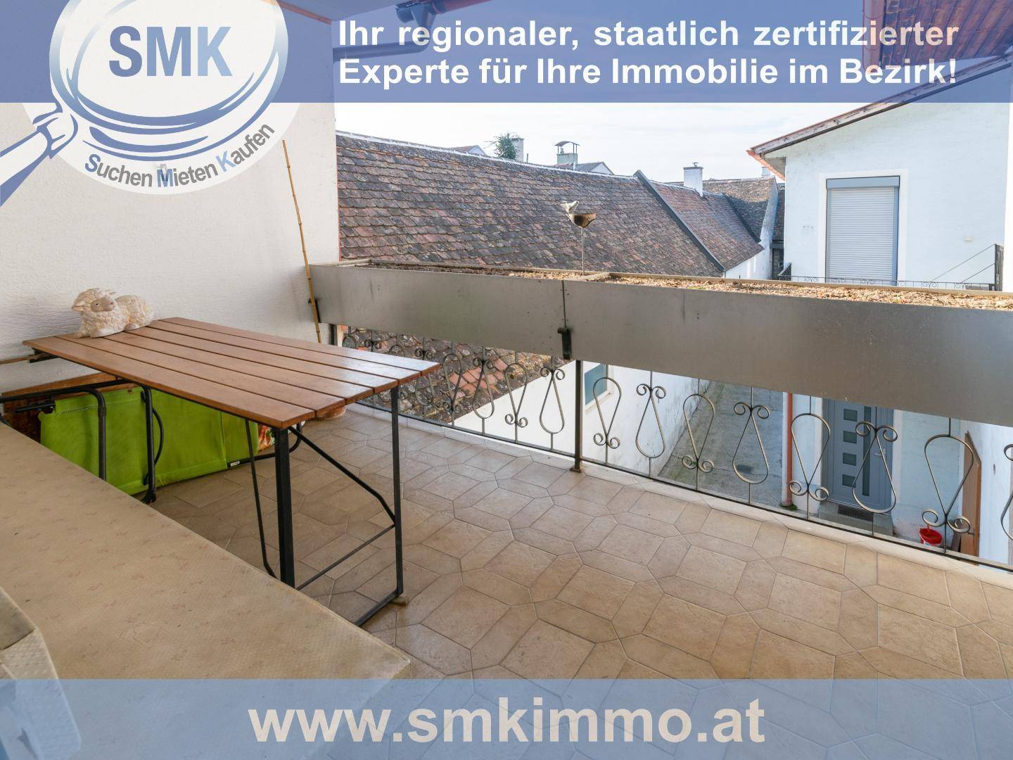 Balkon mit Fliesenboden, kleinem Tisch und Blick über die umliegenden Dächer.