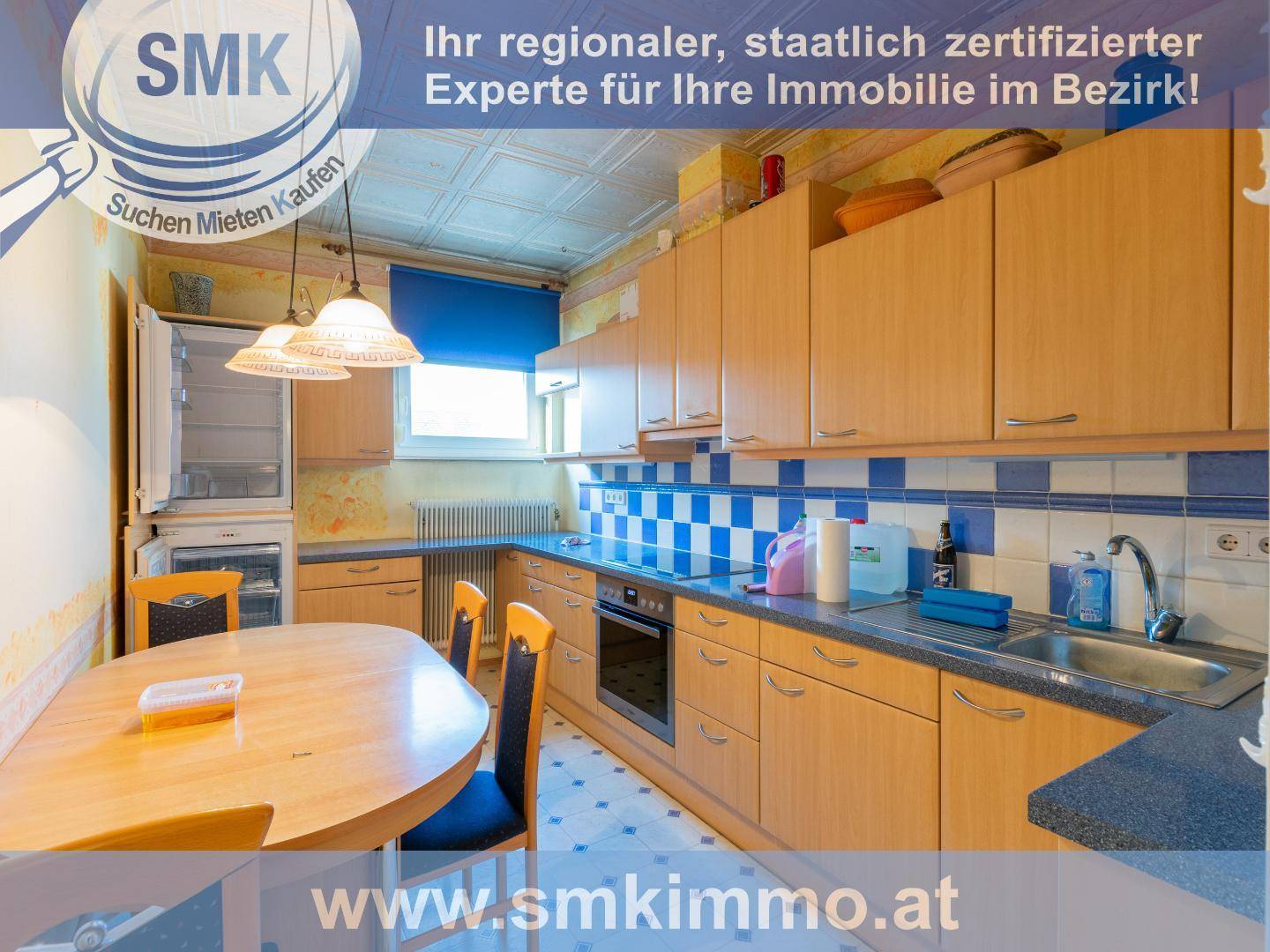 Küche mit Holzschränken, blau-weiß gefliestem Spritzschutz und Essbereich.