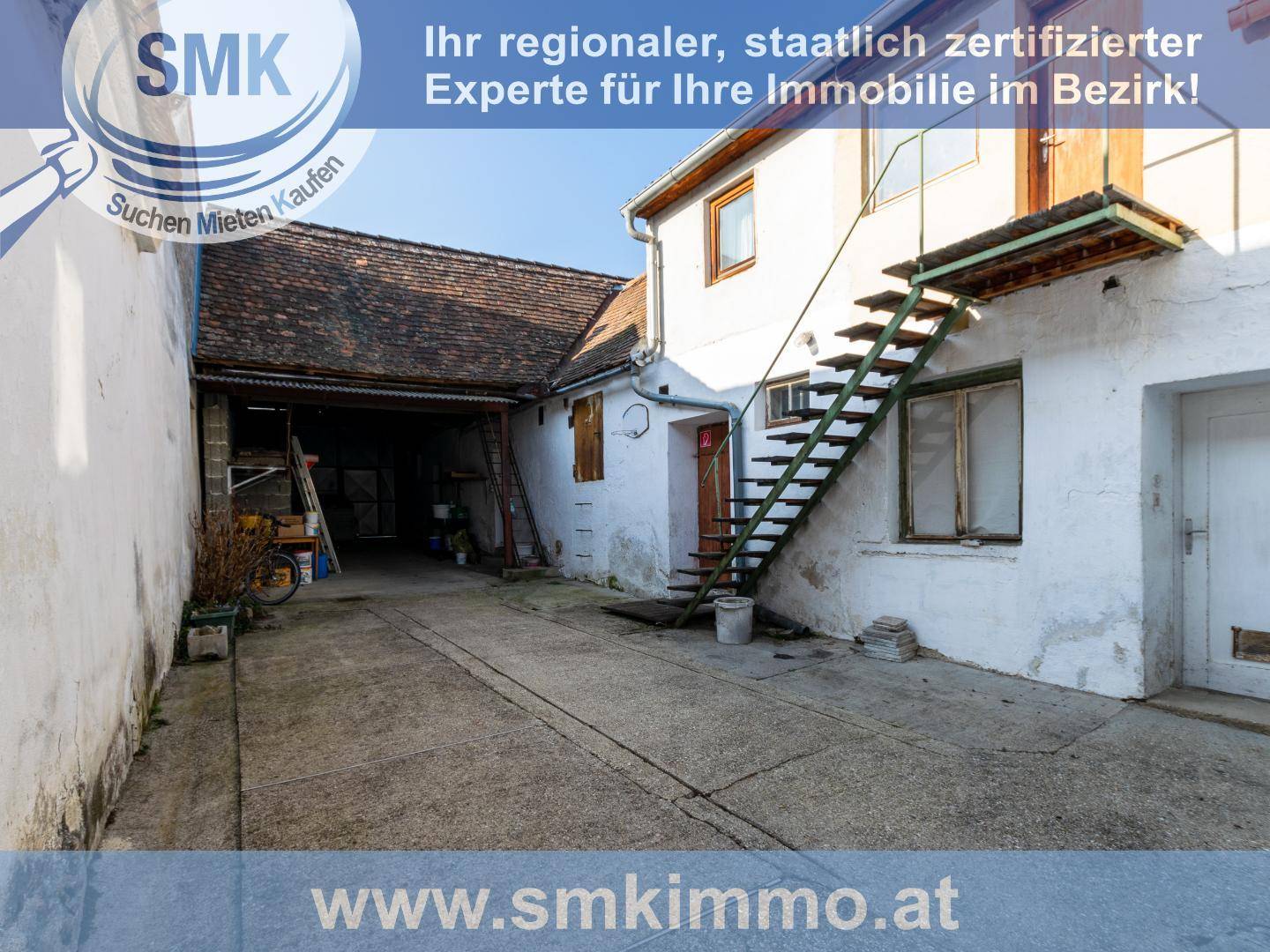 Hinterhof oder Zufahrt mit Außentreppe und Blick auf ältere Gebäude und eine Garage.