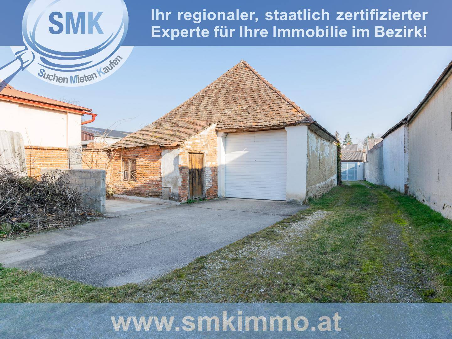 Altes Ziegelgebäude mit großem Garagentor und unbefestigtem Vorplatz.