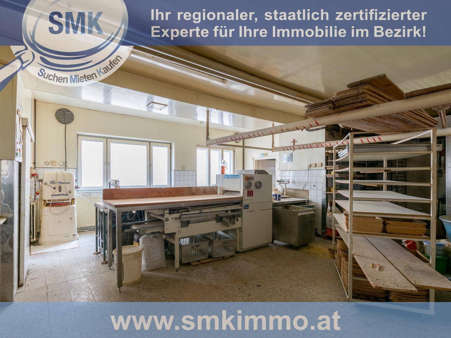 Gewerbliche Küche oder Bäckerei mit professionellen Geräten und großen Fenstern.