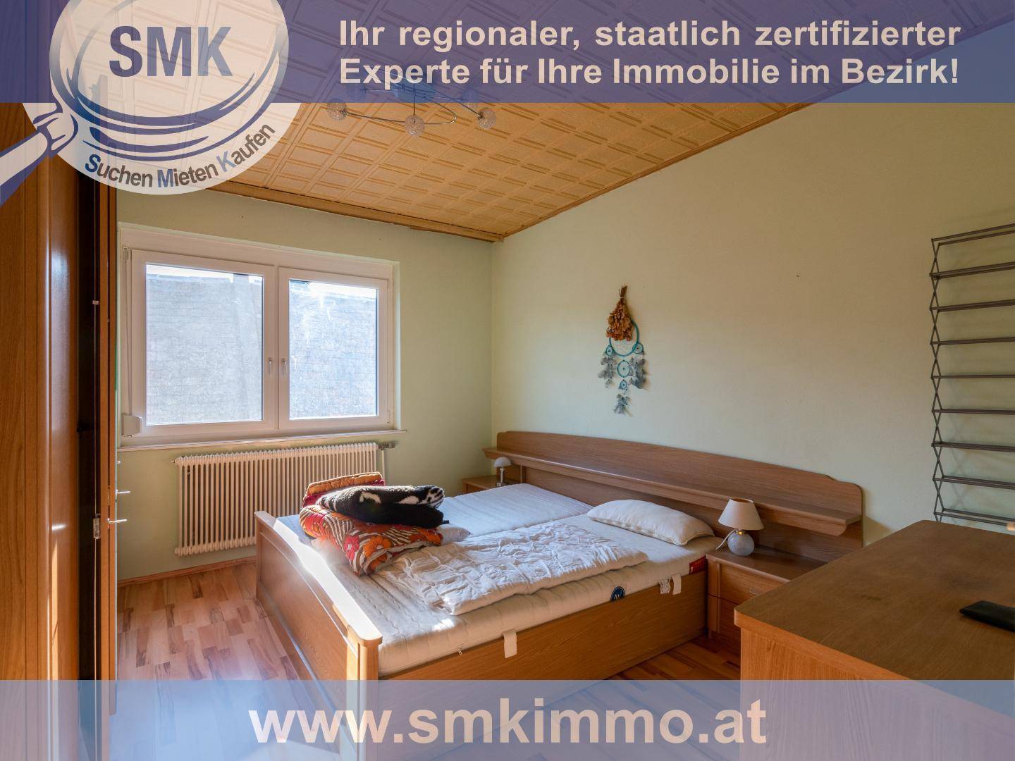 Schlafzimmer mit Doppelbett, Nachttischen, Fenster und einer Holzdecke.