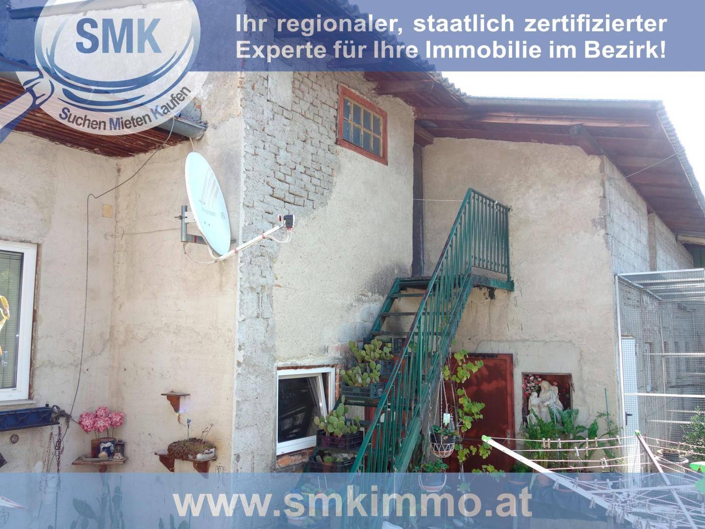 Außenansicht eines Gebäudes mit einer Metalltreppe, Satellitenschüssel und einem kleinen Fenster.
