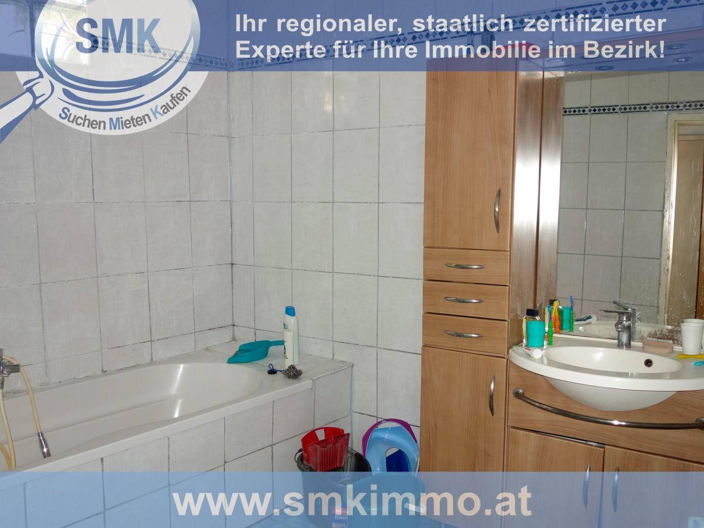 Badezimmer mit Badewanne, Waschbecken und einem Holzschrank, gefliest in Weiß und Blau.