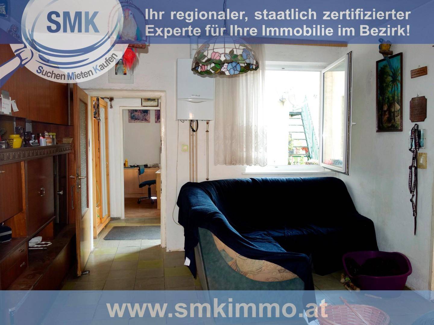 Gemütliches Wohnzimmer mit einem dunkelblauen Sofa, einem Fenster und Blick in ein angrenzendes Zimmer.