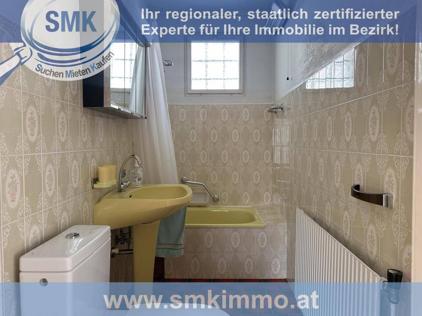 Badezimmer im 80er-Jahre-Stil mit gelber Badewanne, Waschbecken und gemusterten Fliesen.