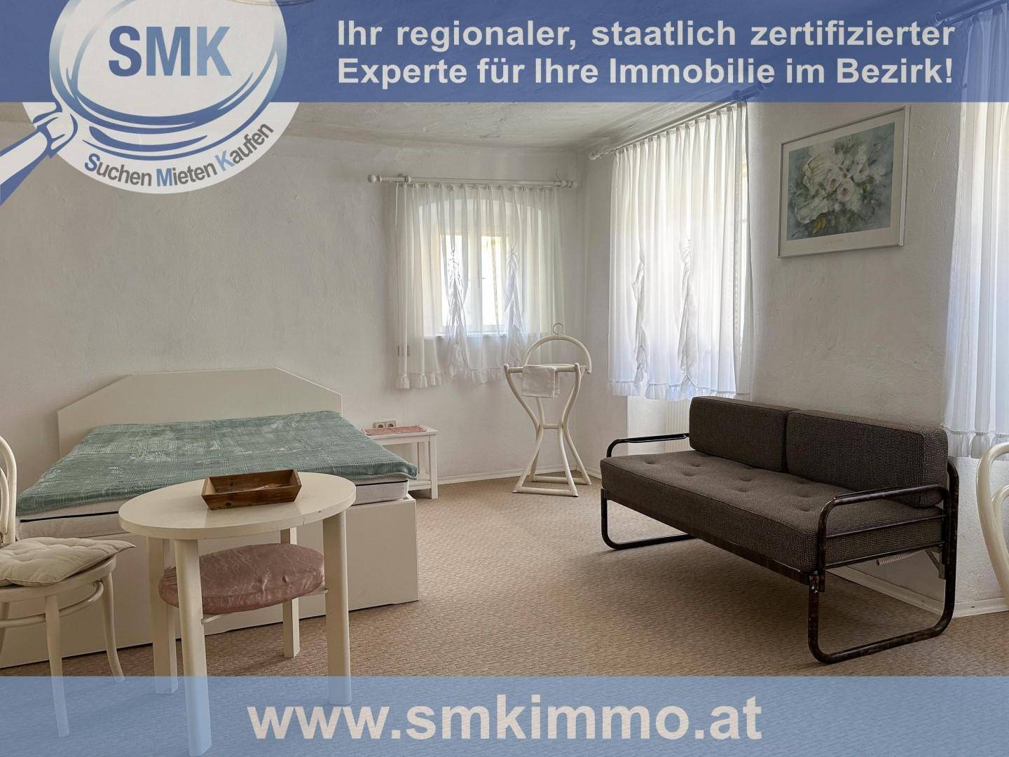 Geräumiges Schlafzimmer mit Bett, Sofa und hellen Vorhängen an den Fenstern.