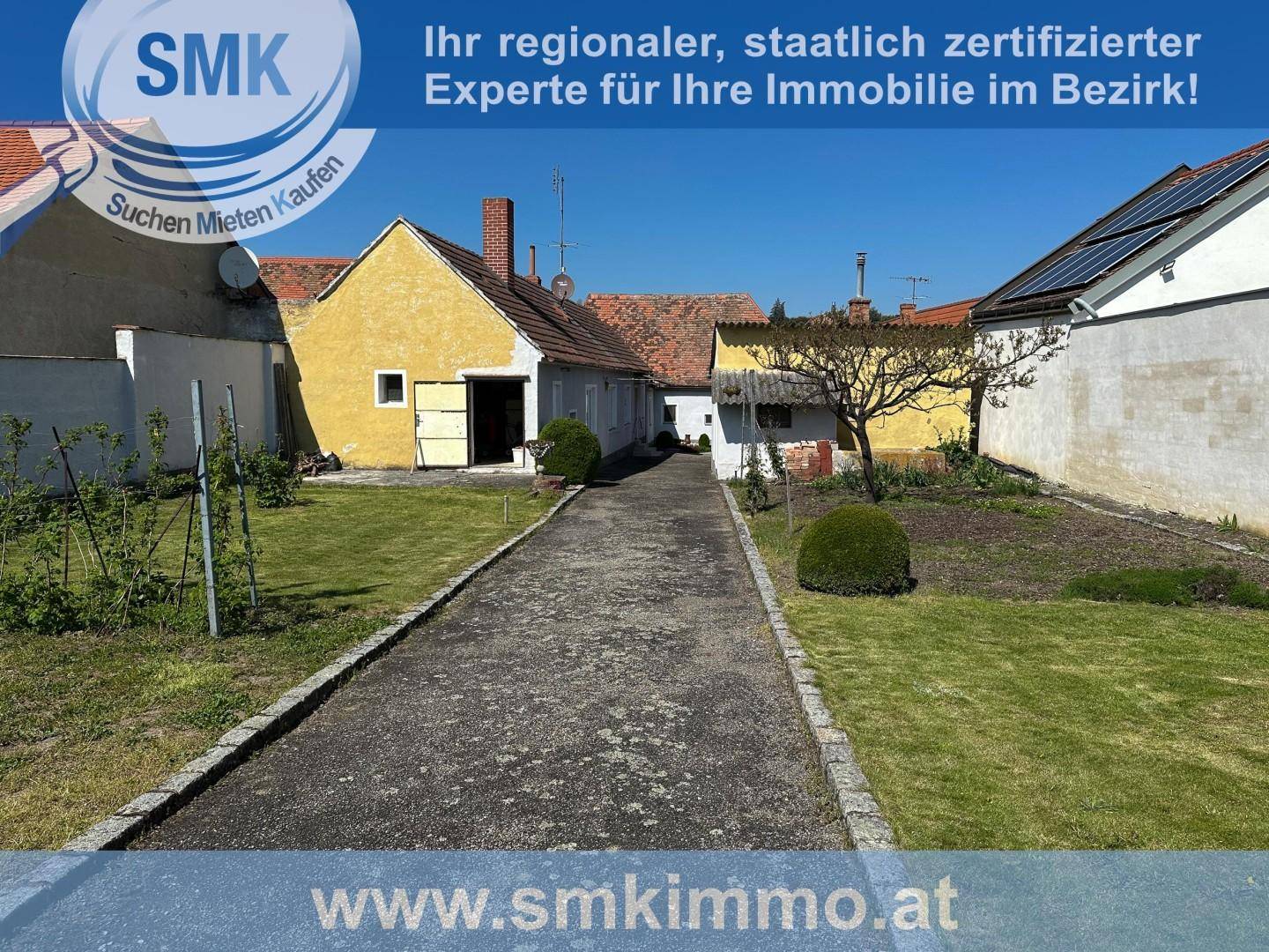 Weitläufiger Garten mit einem gepflasterten Weg und Blick auf die angrenzenden Gebäude.