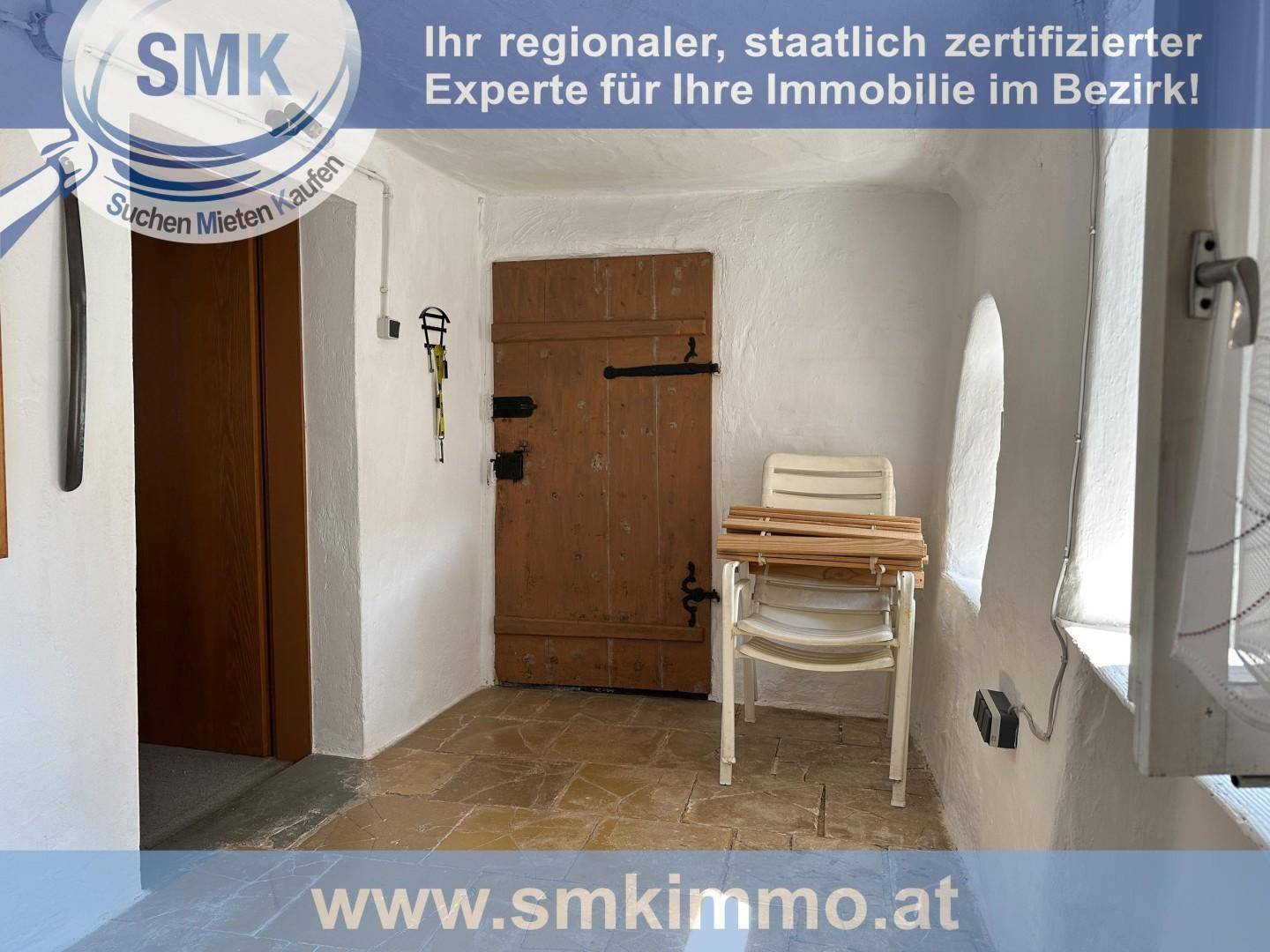 Rustikaler Eingangsbereich mit Holztür, Steinboden und gewölbter Wand.