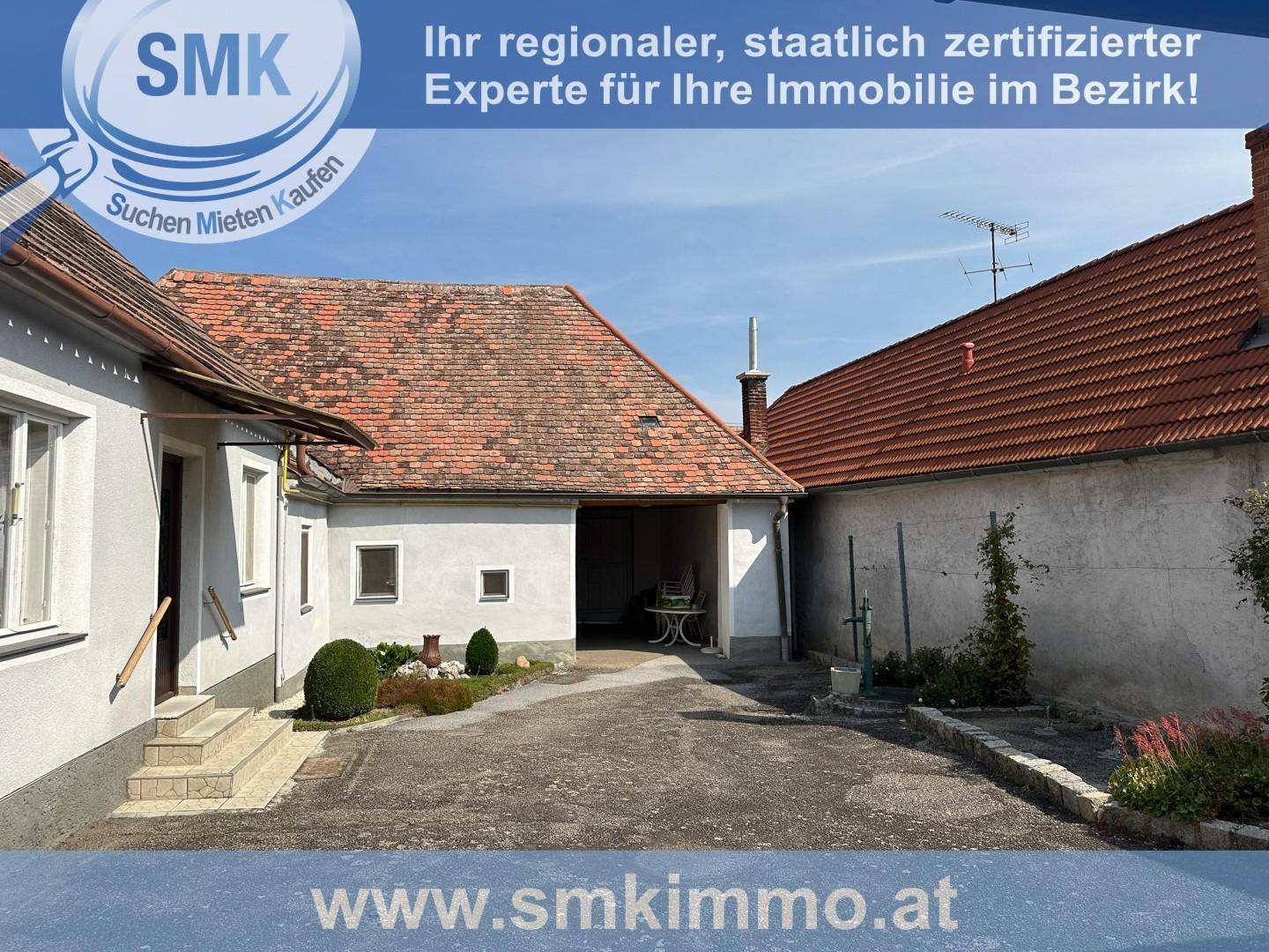 Innenhofbereich mit Kiesweg zwischen den Gebäuden und einem kleinen Sitzbereich im Freien.