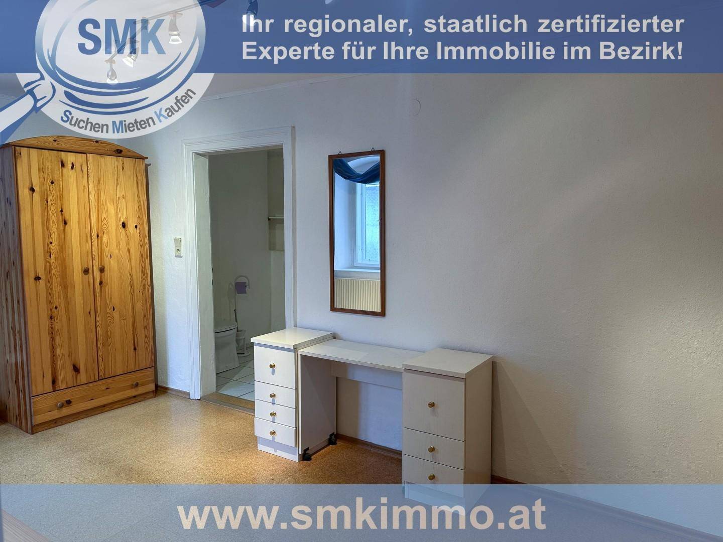 Schlafzimmer mit Holzschrank, Schminktisch und hellem Bodenbelag.