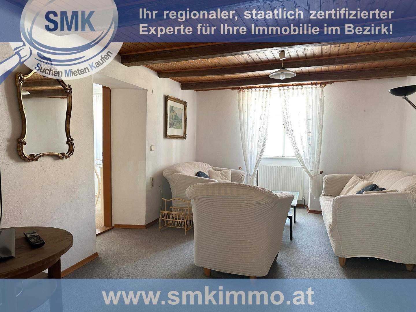 Gemütliches Wohnzimmer mit Holzbalkendecke, bequemen Sofas und traditionellem Spiegel.