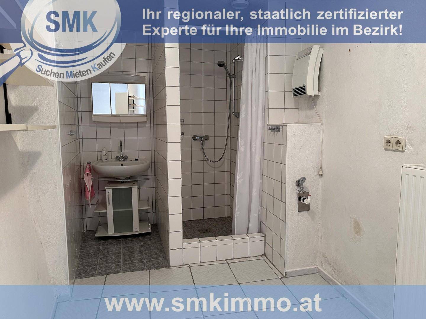 Einfaches Badezimmer mit Duschbereich, Waschbecken und weißen Fliesen.