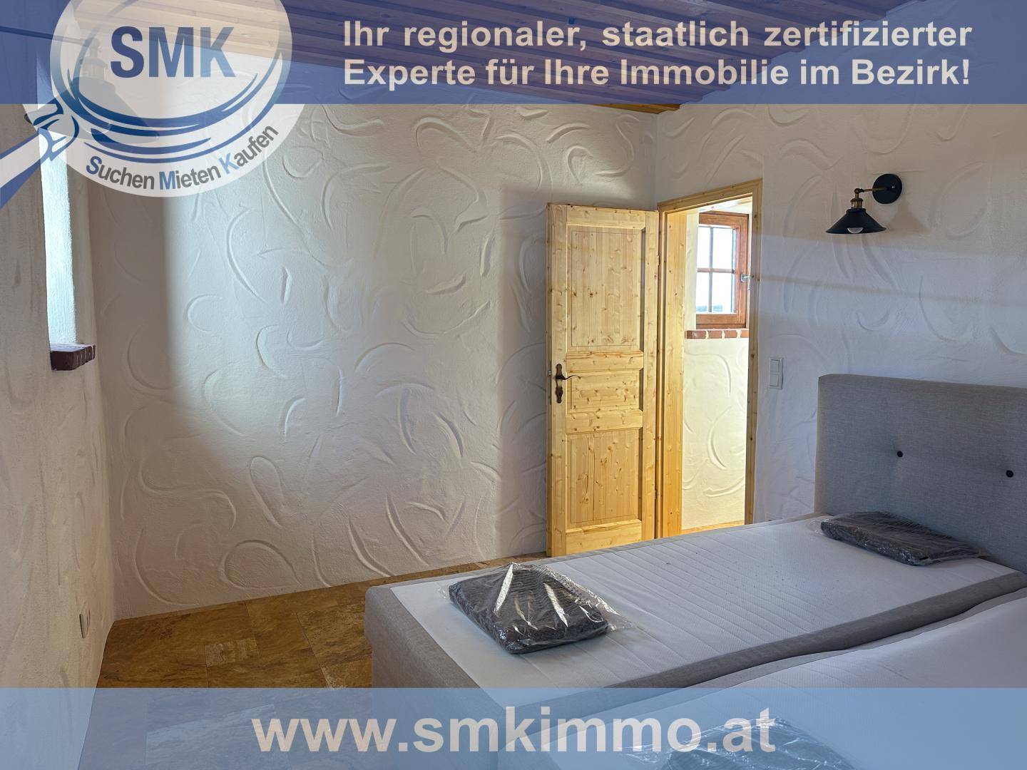 Schlafzimmer mit Holzbalkendecke, strukturierten Wänden und einem einfachen Bett.