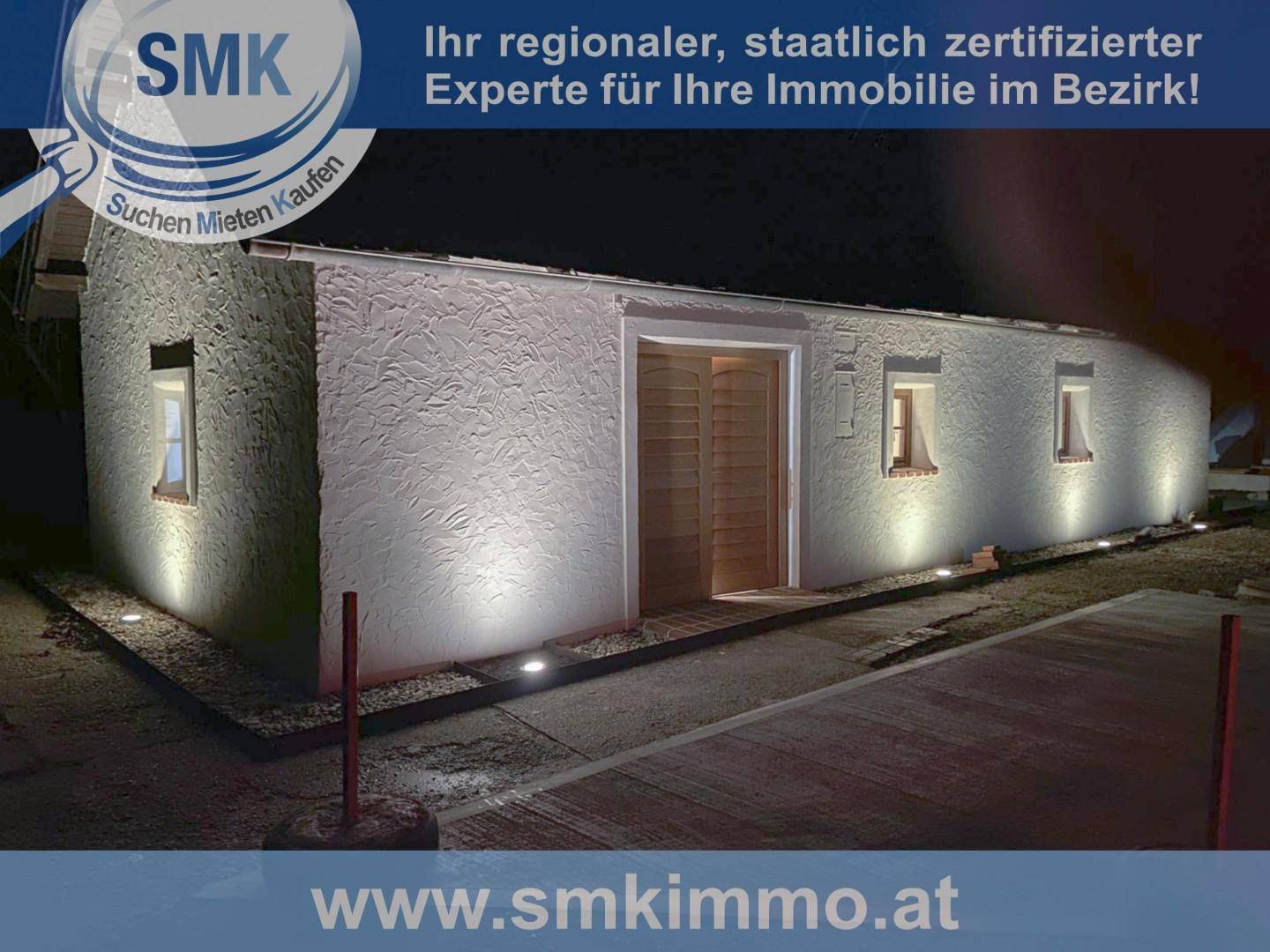 Beleuchtete Fassade des weißen Hauses bei Nacht mit strukturiertem Putz.