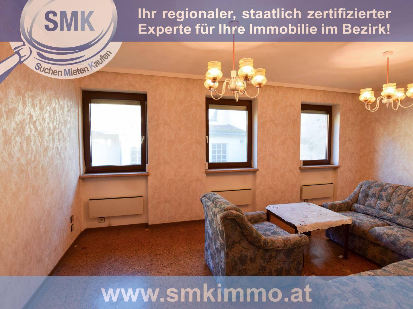 Wohnzimmer mit gemusterter Tapete, traditionellen Möbeln und zwei Kronleuchtern.