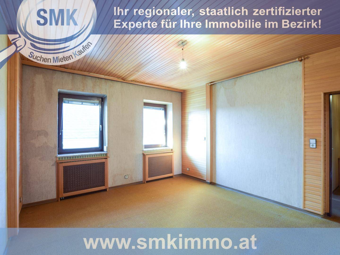 Geräumiges Zimmer mit Holzdeckenverkleidung, Teppichboden und zwei Fenstern mit Heizkörpern.