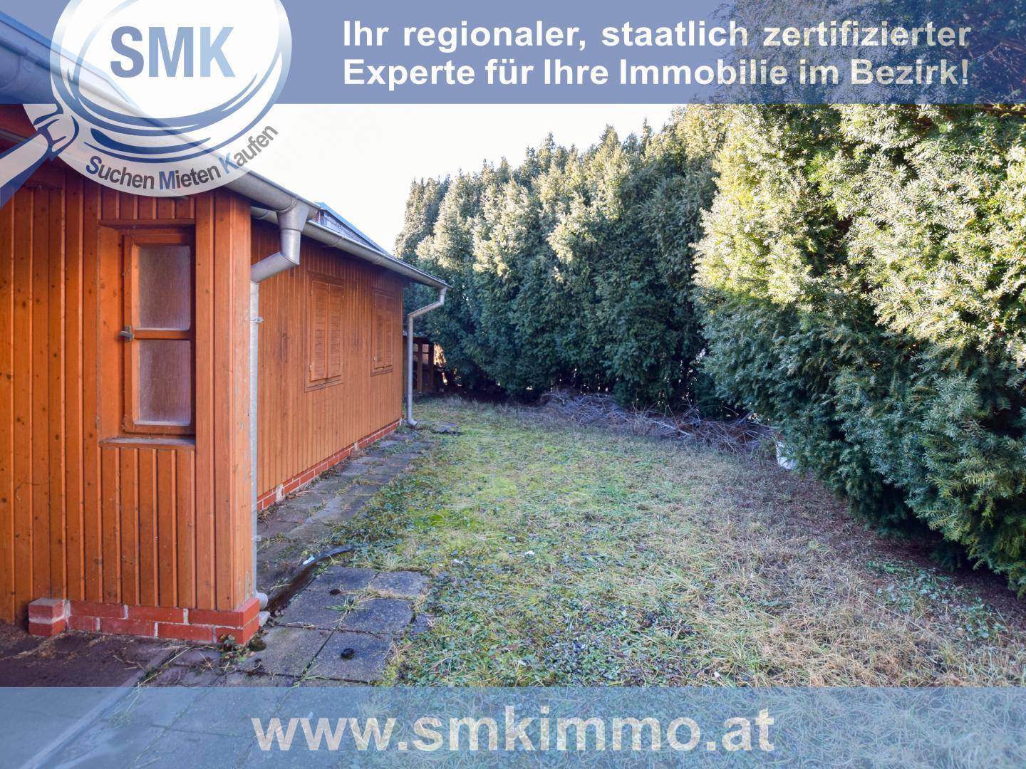 Gartenbereich mit Rasenfläche, hohen Hecken und einem Holzschuppen am Rand des Grundstücks.