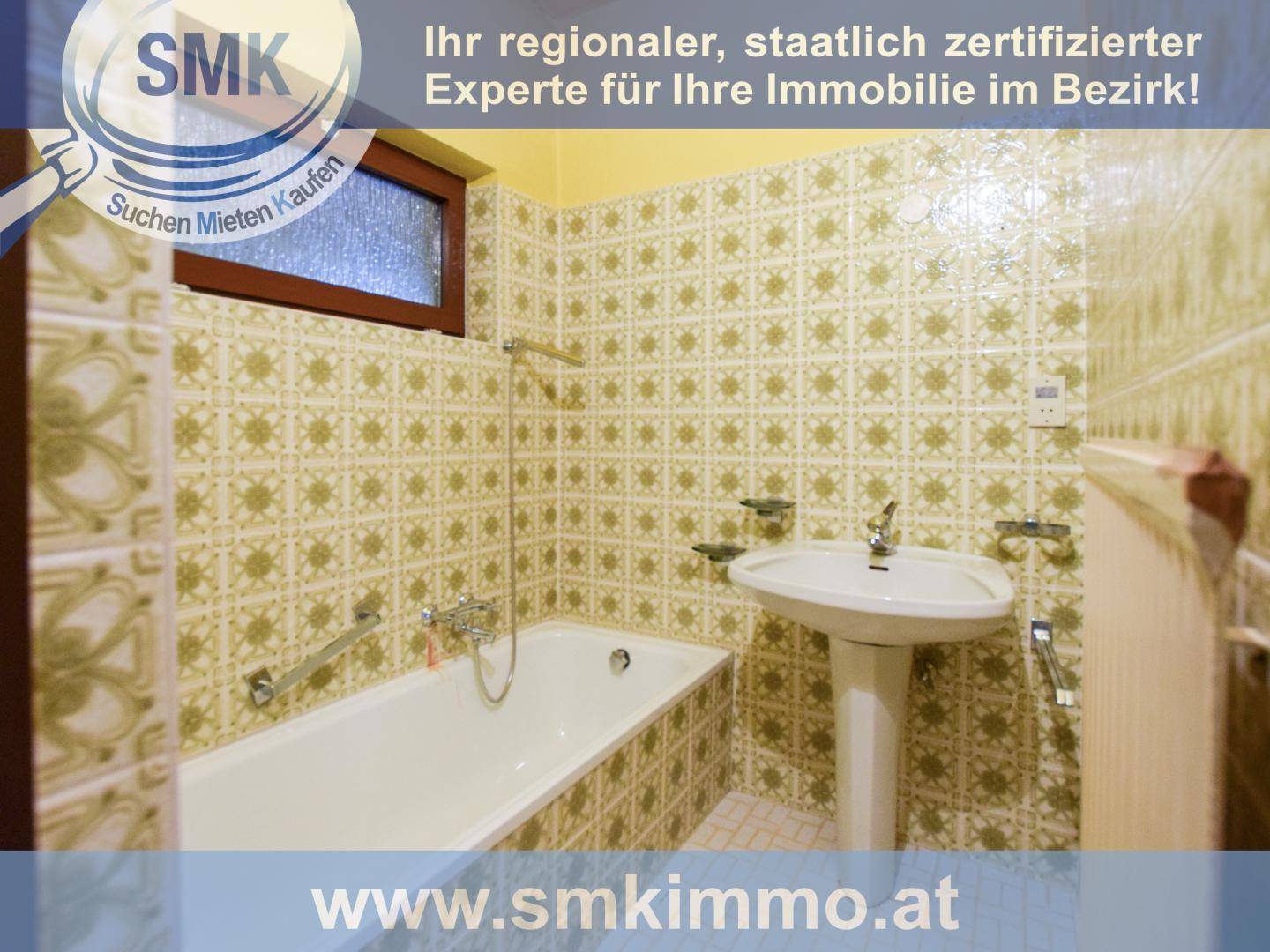 Badezimmer mit Badewanne, Waschbecken und gemusterten Wandfliesen im Stil der 80er Jahre.