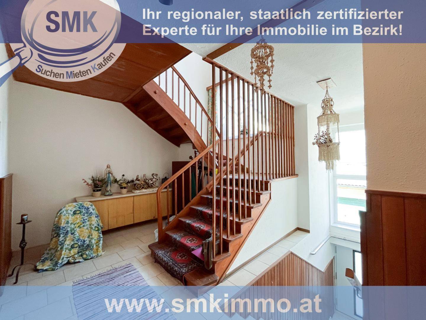 Geräumiger Flur mit einer markanten Holztreppe und traditionellen Dekorationen.