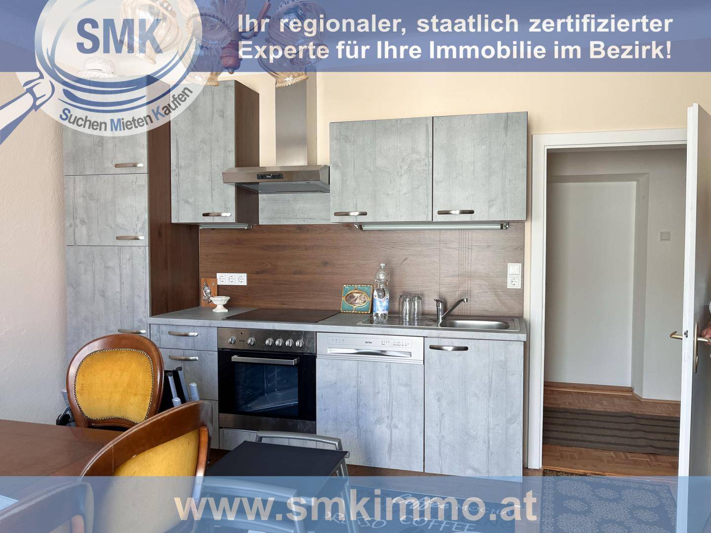 Kompakte Küche mit grauen Schränken, integrierten Geräten und Essbereich.