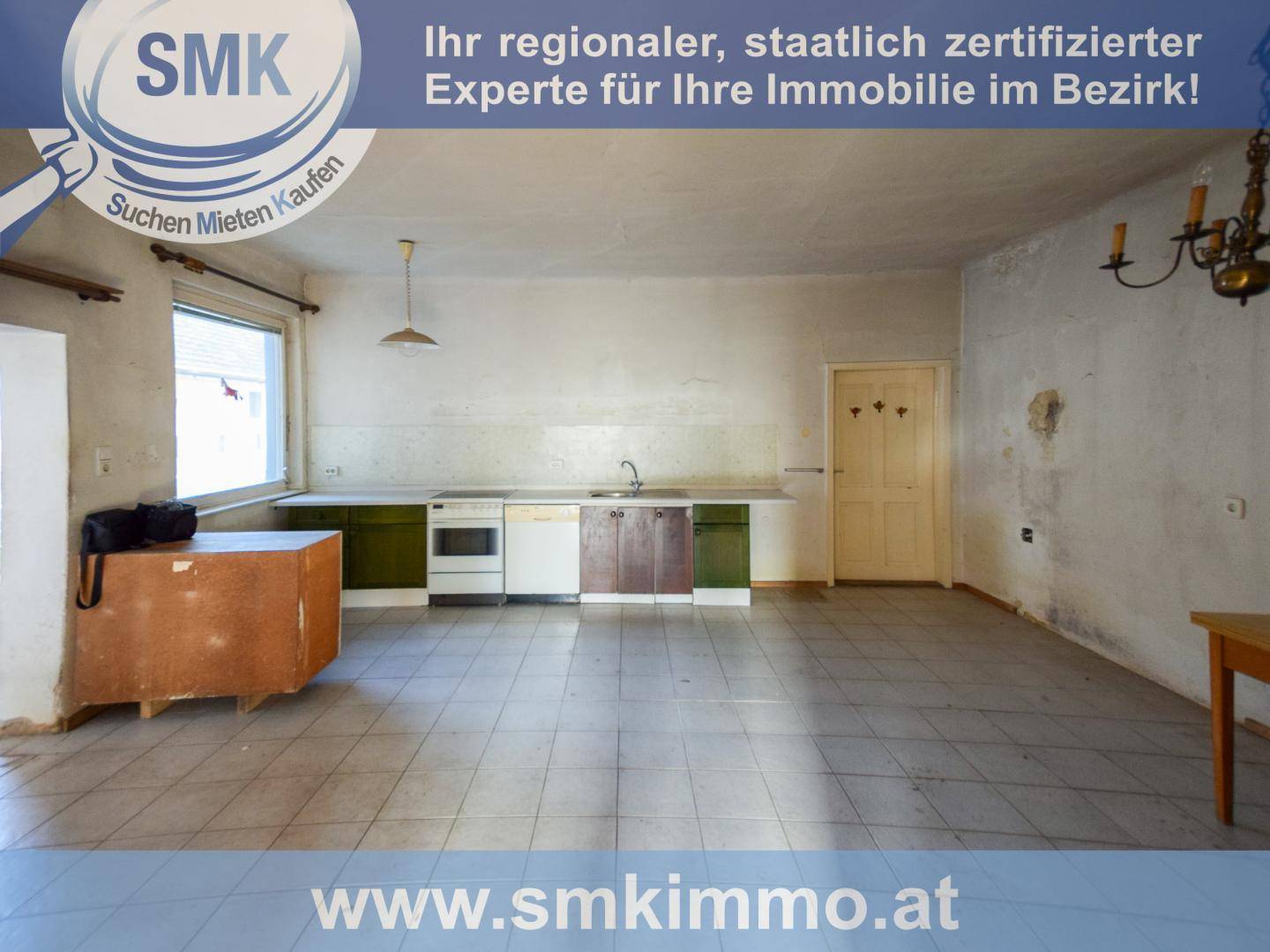 Alte Küche mit Fliesenboden, einfachen Schränken und einem Herd, die Renovierung benötigt.