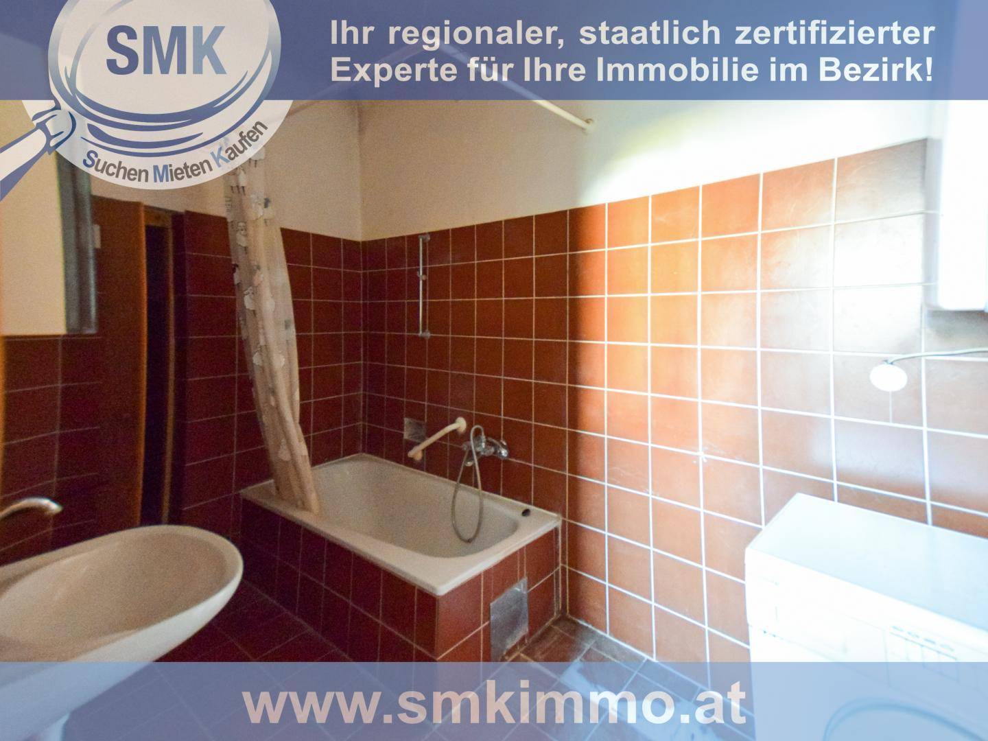Badezimmer mit braunen Fliesen, einer Badewanne und einem Waschbecken, das einen älteren Stil aufweist.
