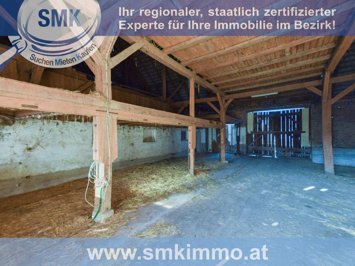 Geräumige Scheune mit sichtbaren Holzkonstruktionen und Stroh auf dem Boden, bereit zur Nutzung.