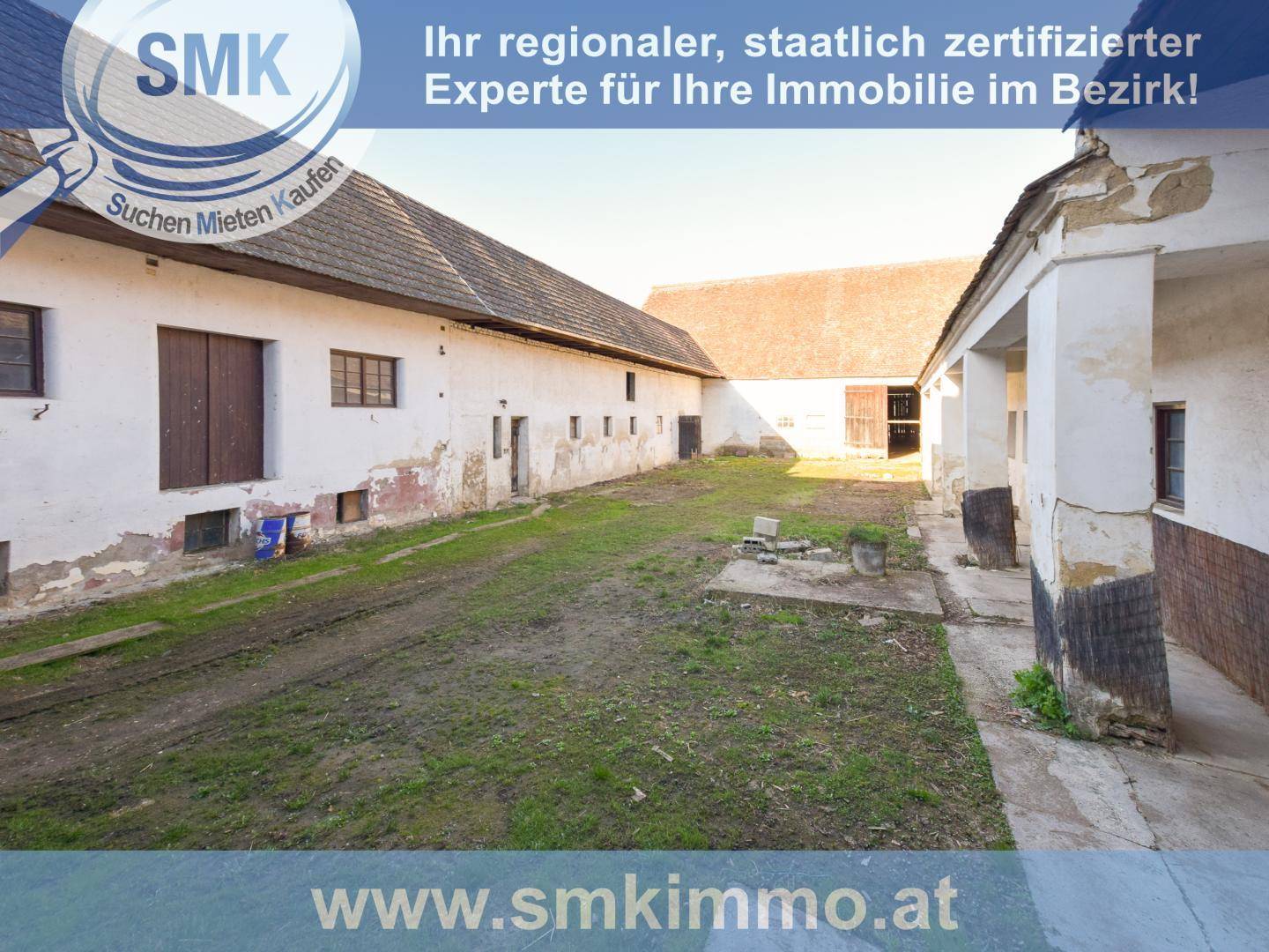 Weitläufiger Innenhof eines alten Anwesens mit mehreren Gebäuden und unbefestigtem Boden.