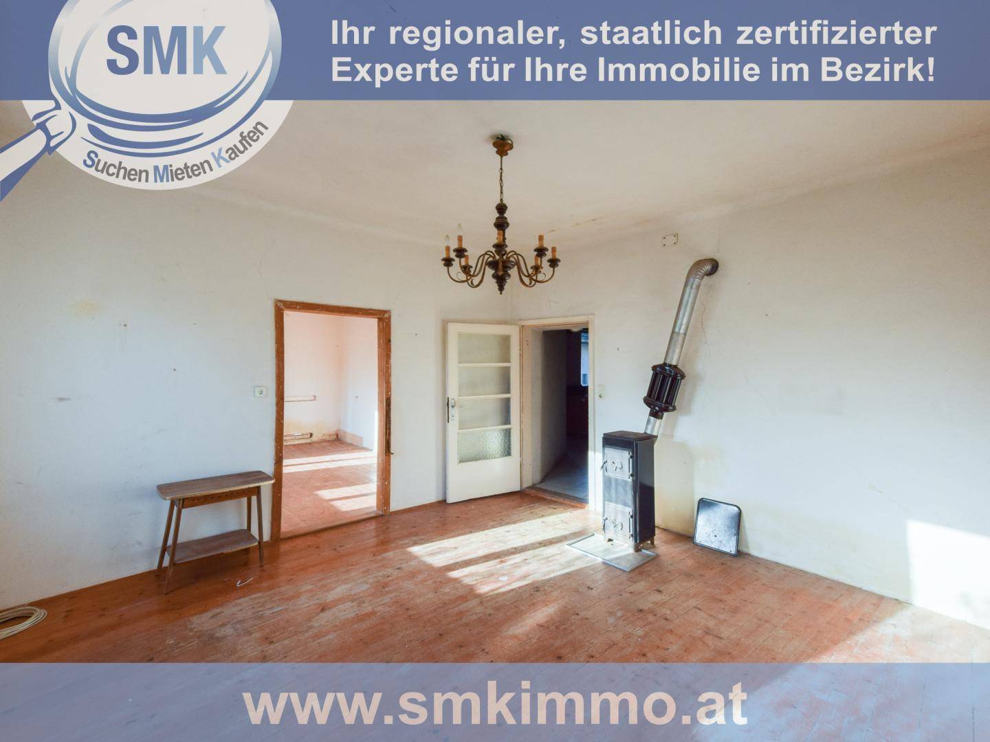 Leeres Zimmer mit Holzdielenboden und einem modernen Holzofen, der als Heizquelle dient.