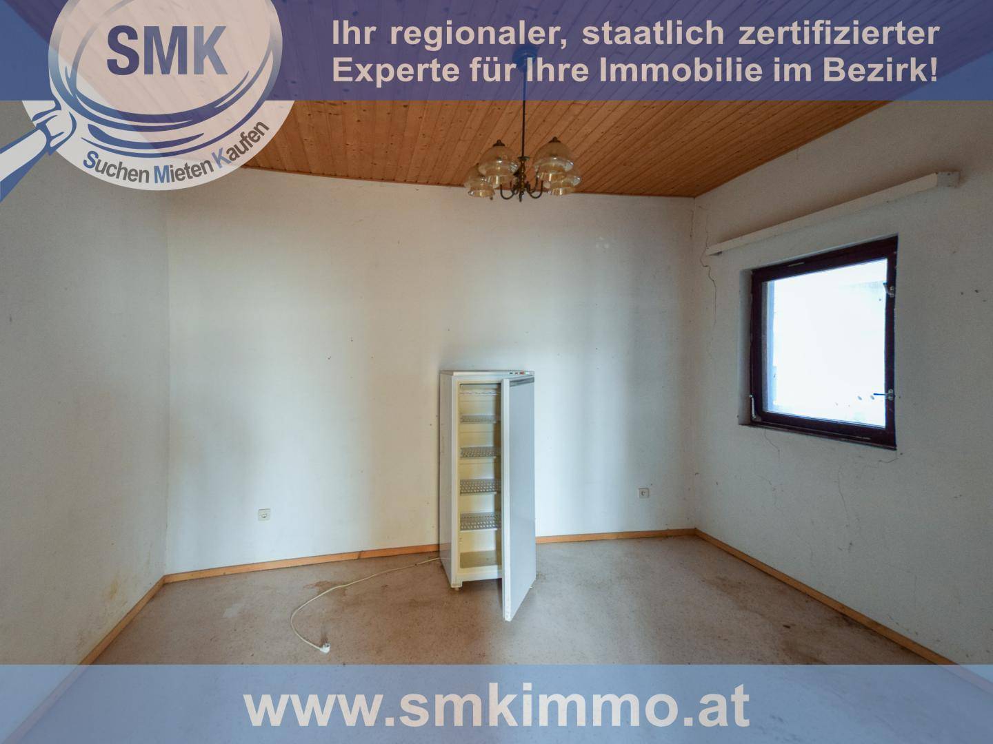 Leeres Zimmer mit Holzdeckenverkleidung und einem kleinen Kühlschrank, bereit zur individuellen Gestaltung.