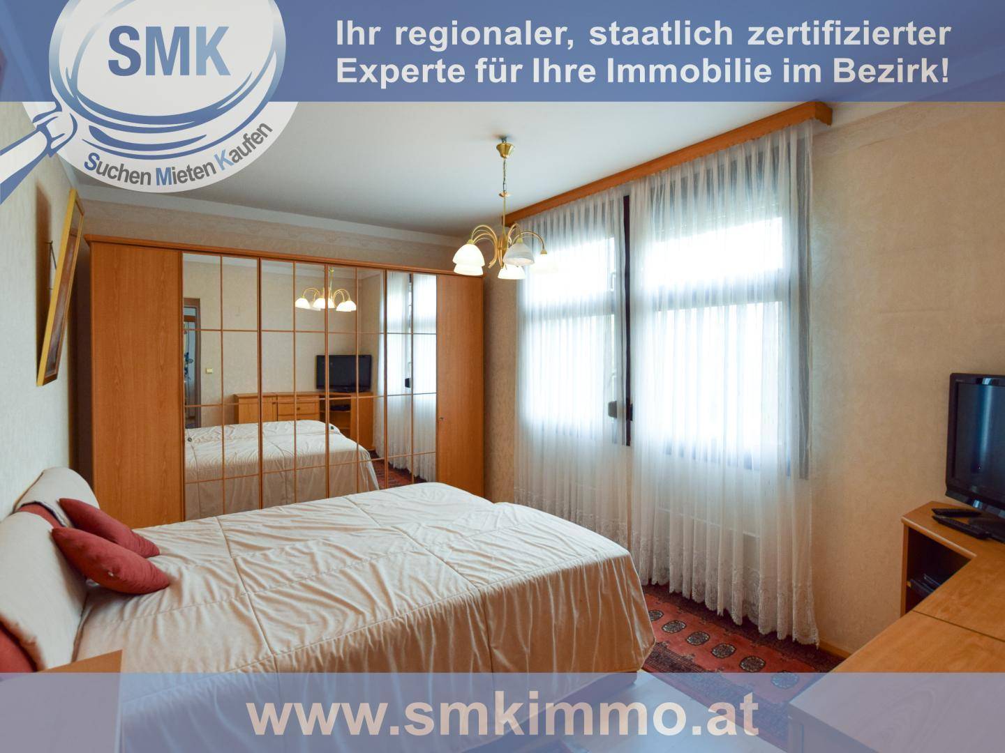 Schlafzimmer mit Doppelbett, Spiegelschrank und hellen Vorhängen an den Fenstern.