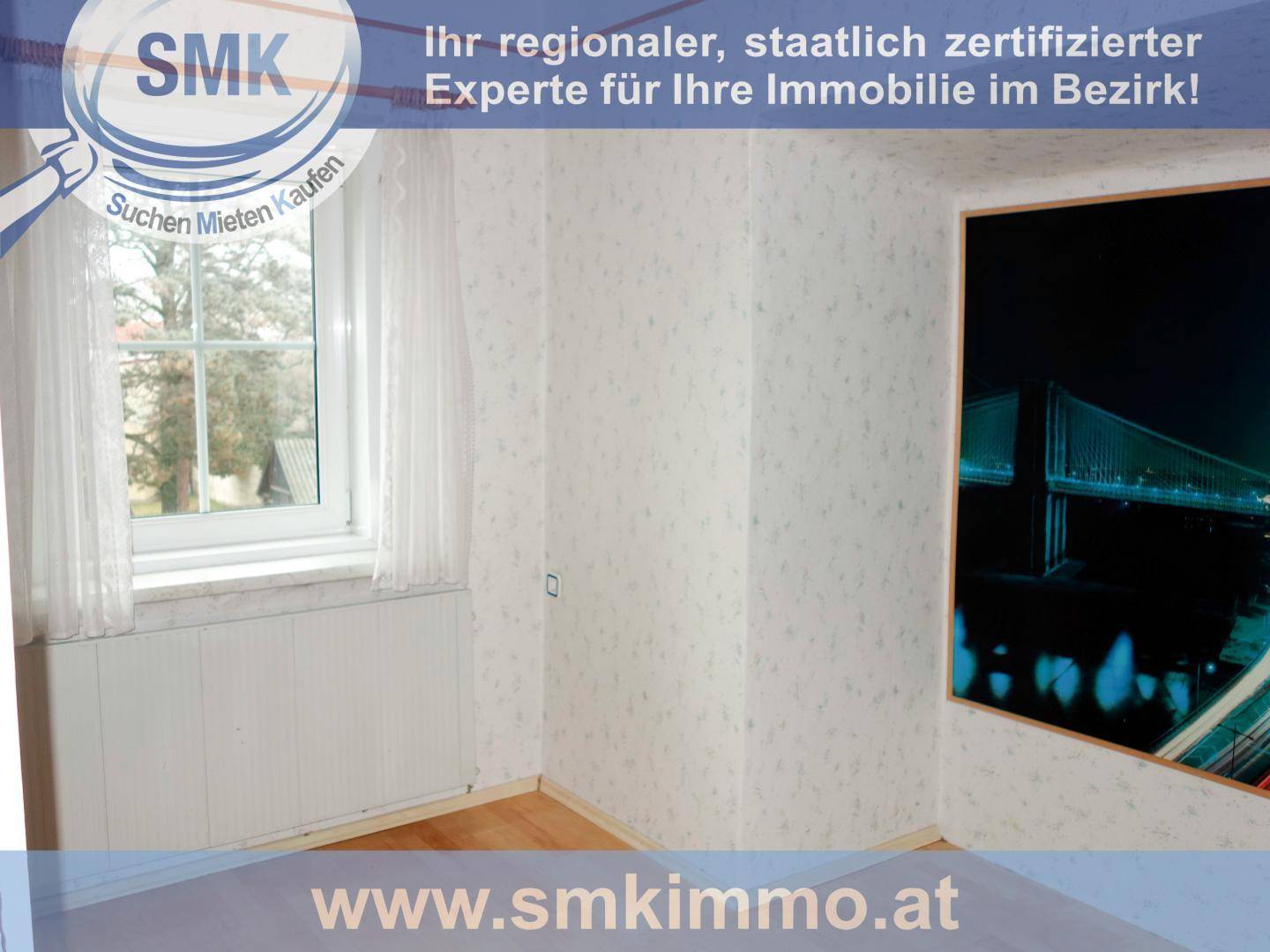 Zimmer mit Laminatboden, gemusterter Tapete und Blick ins Grüne durch das Fenster.