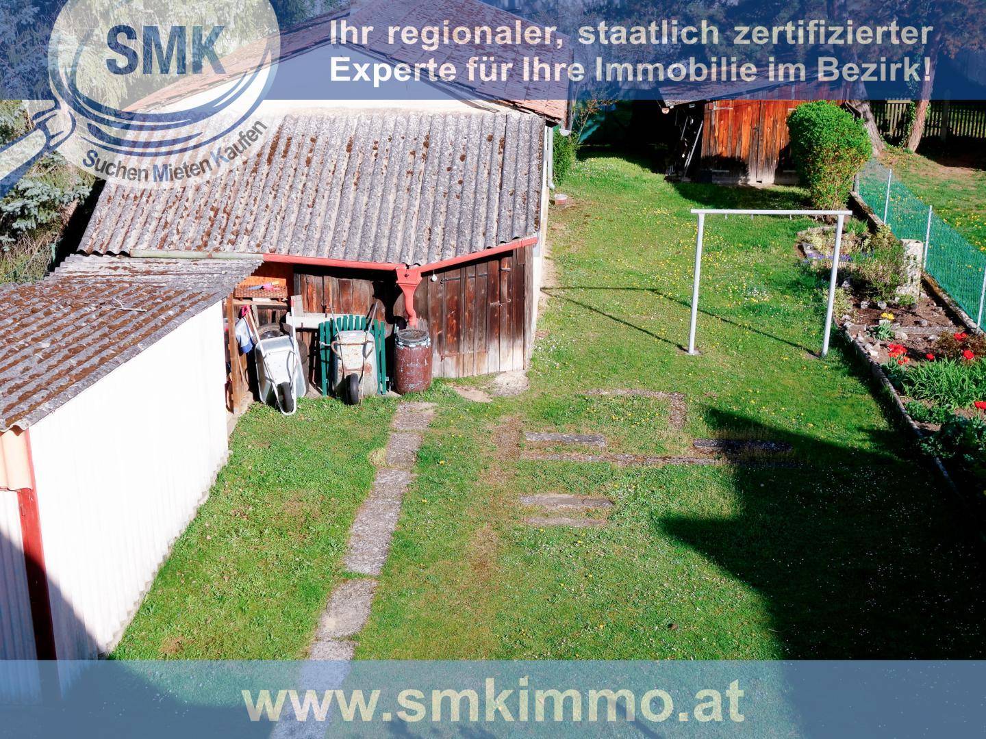 Gartenbereich mit Rasenfläche, einem Schuppen und Wäscheleine im Freien unter blauem Himmel.