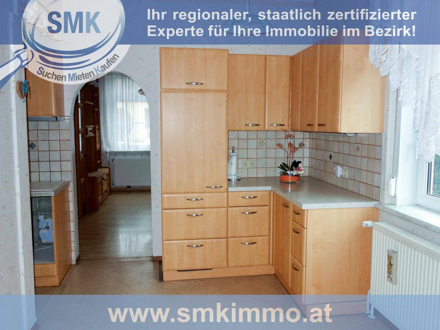 Helle Küche mit hellen Holzschränken, Fliesenrückwand und Fenster mit Tageslichteinfall.