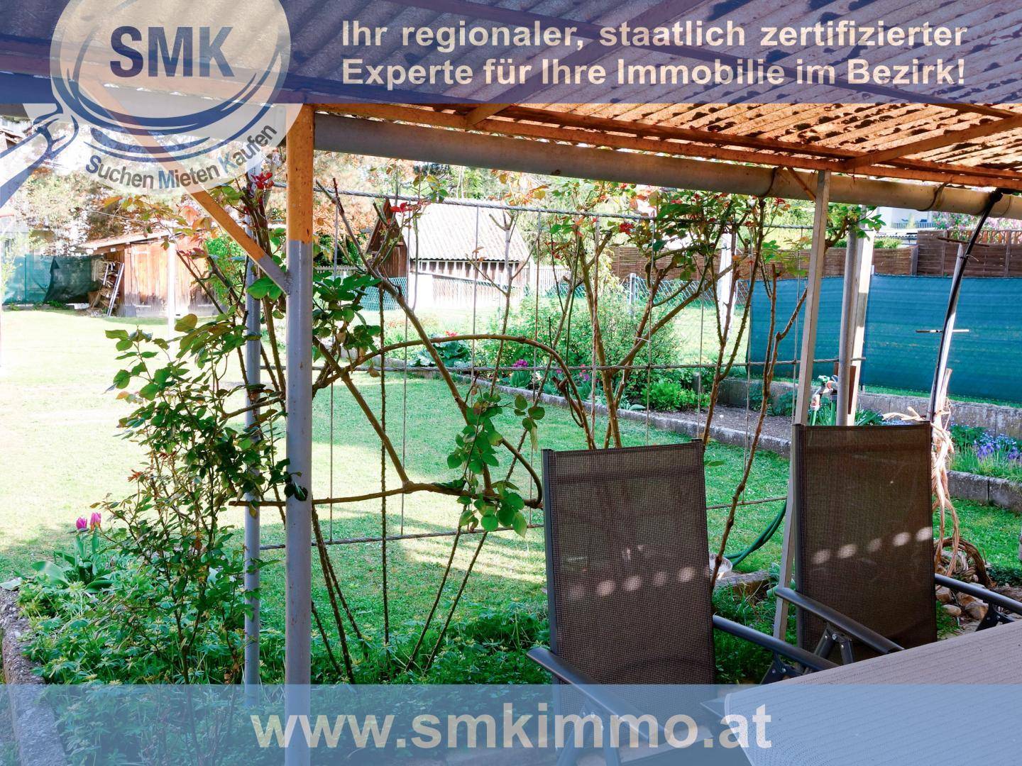 Überdachter Sitzbereich im Garten mit Gartenmöbeln und Rosensträuchern an einem sonnigen Tag.