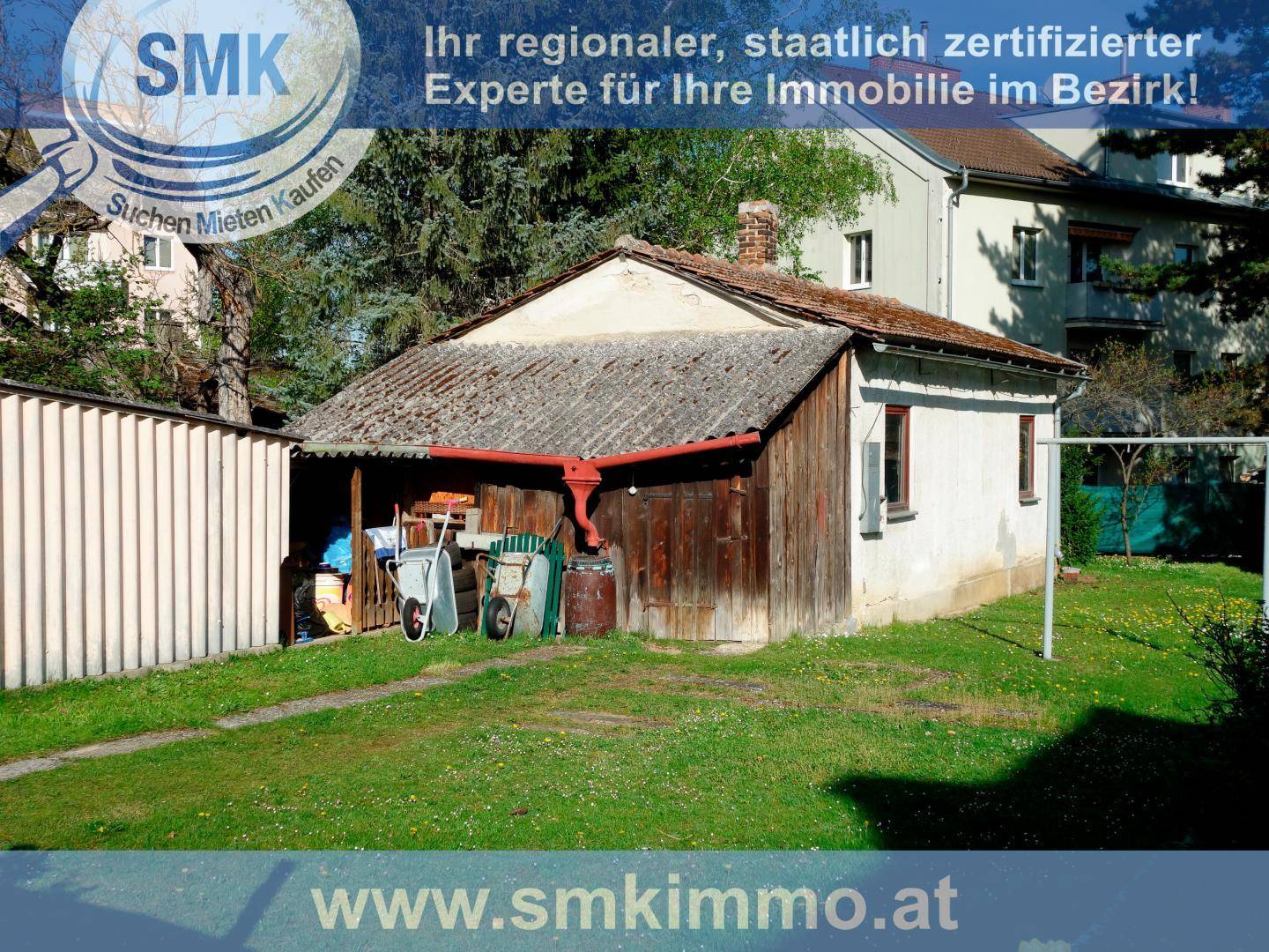 Gartenbereich mit Rasenfläche, einem alten Schuppen und Geräten für die Gartenarbeit.