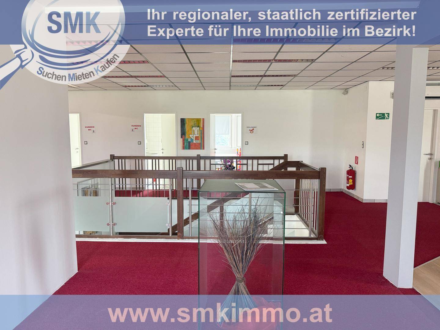 Heller Bürobereich mit rotem Teppichboden und moderner Glas-Holz-Treppengalerie.