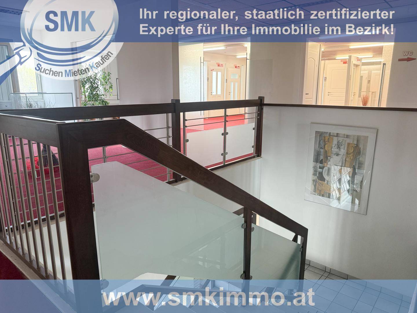 Treppenabsatz mit eleganter Holz-Glas-Brüstung, rotem Teppichboden und einem Kunstwerk an der Wand.
