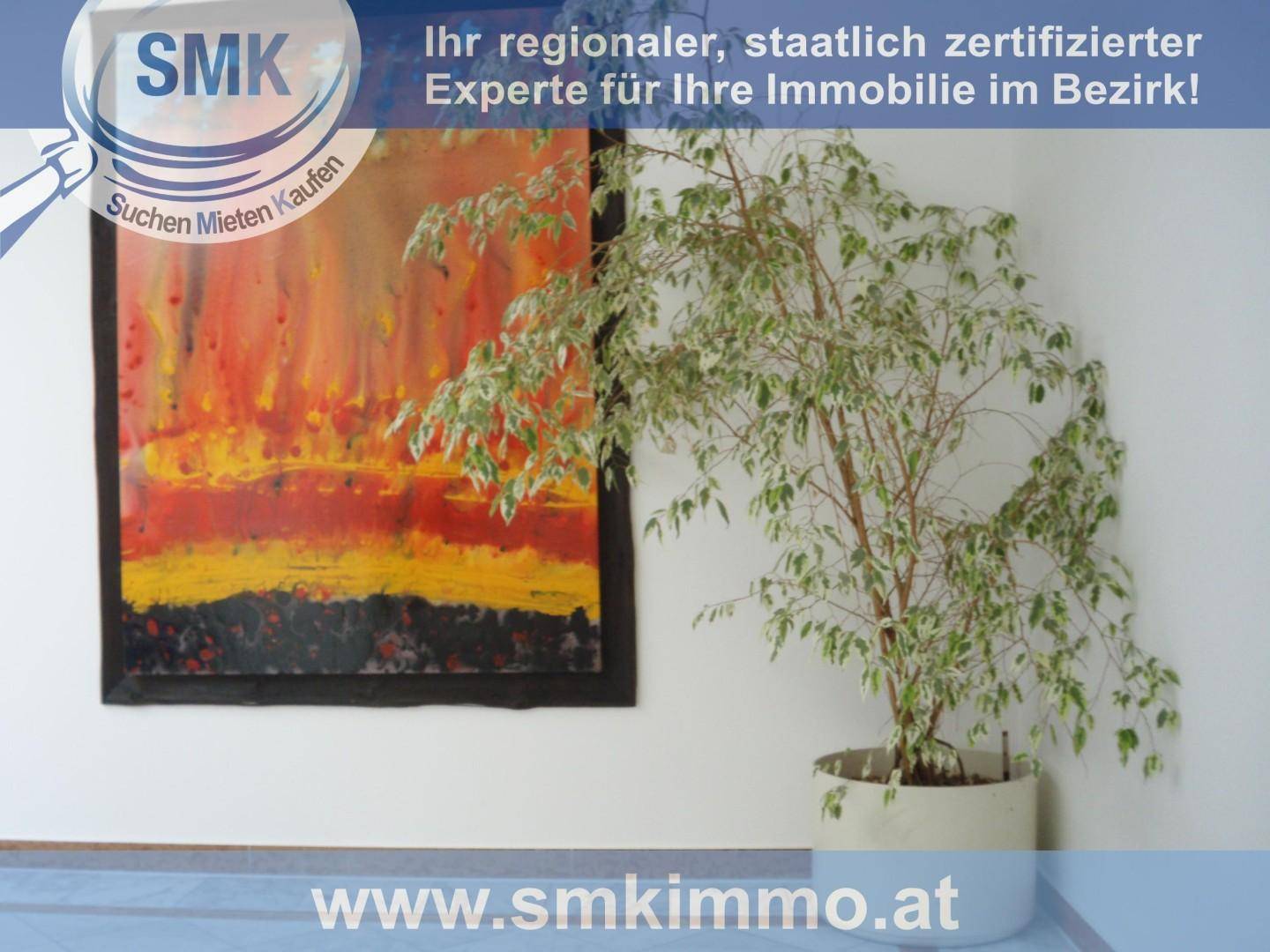 Innenraum mit einer großen Zimmerpflanze und einem farbenfrohen abstrakten Gemälde an der weißen Wand.