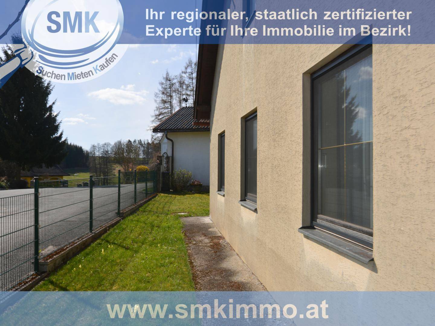 Seitenansicht des Hauses mit Fenstern und gepflegtem Rasen.