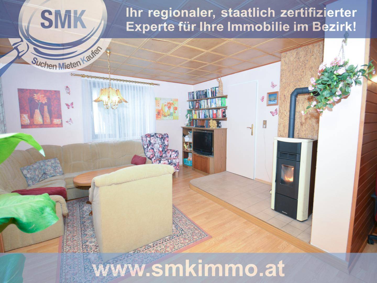 Gemütliches Wohnzimmer mit Kaminofen, Sofa und Holzdecke.