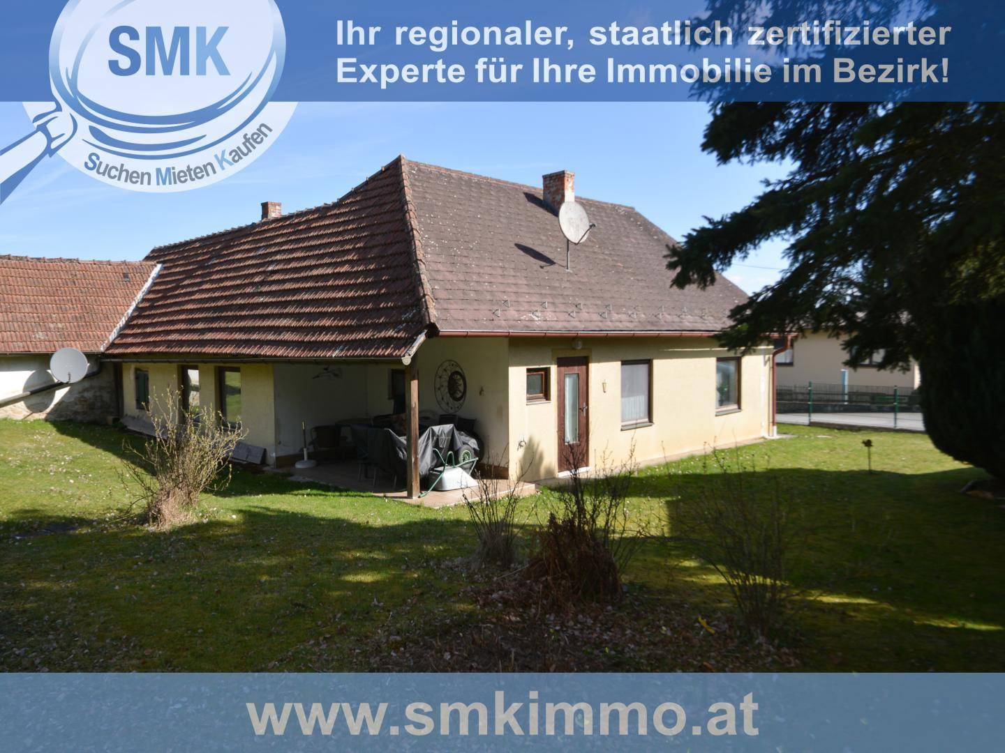 Rückansicht des Hauses mit überdachtem Bereich und weitläufigem Garten.