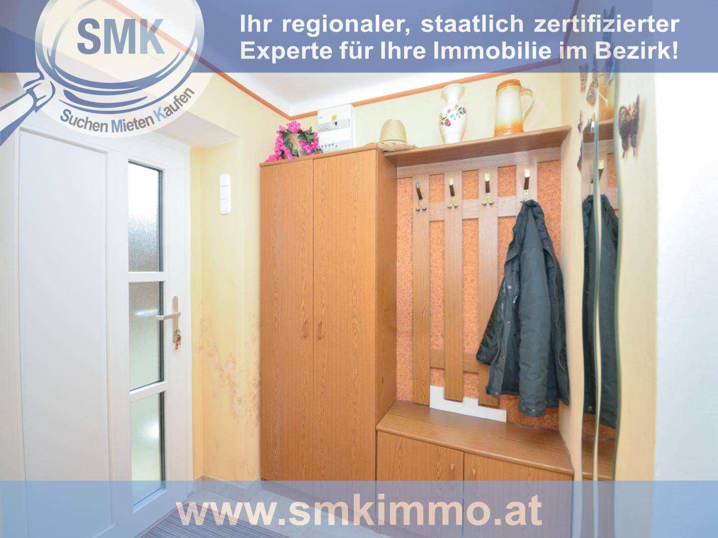 Eingangsbereich mit Garderobe, Spiegelschrank und heller Holztür.